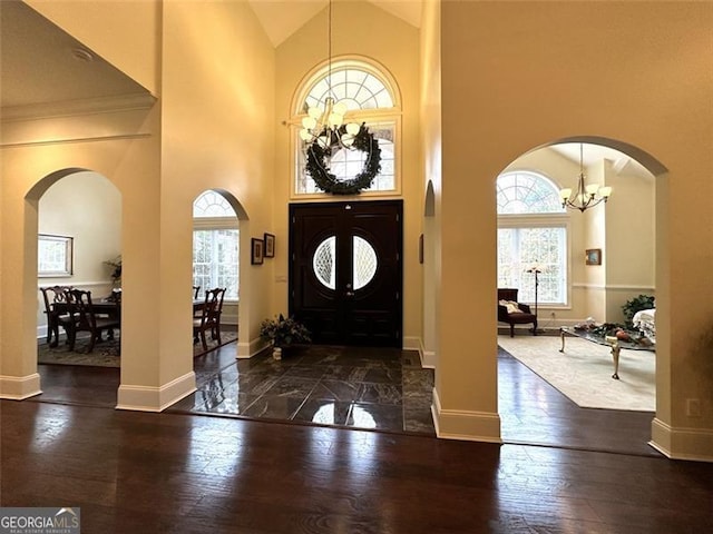 entryway with a high ceiling, dark hardwood / wood-style flooring, and an inviting chandelier