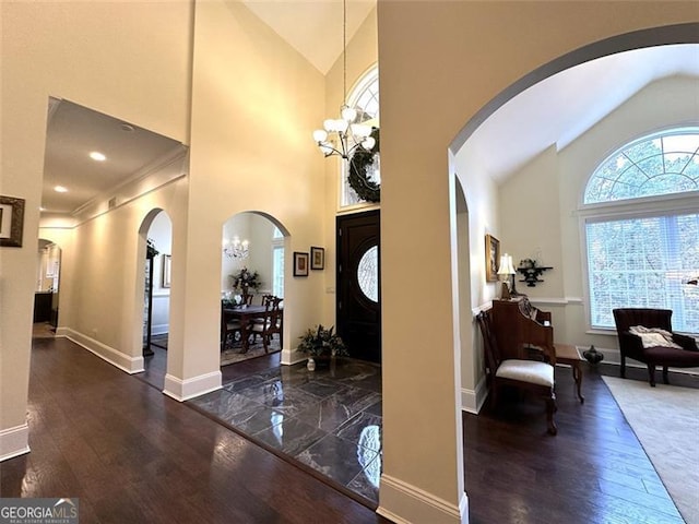 entryway with a chandelier, high vaulted ceiling, and dark wood-type flooring