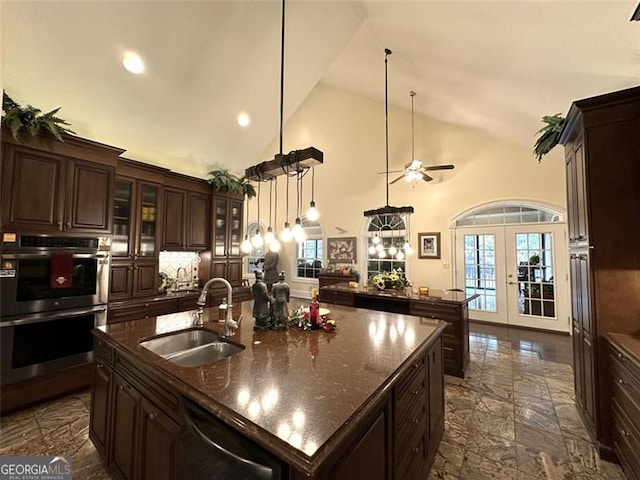 kitchen featuring sink, french doors, stainless steel appliances, high vaulted ceiling, and a kitchen island with sink