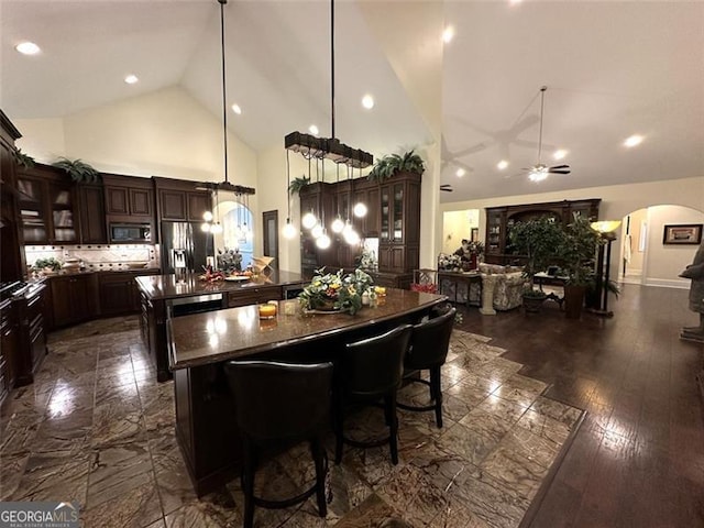 dining space with ceiling fan, high vaulted ceiling, and dark hardwood / wood-style floors