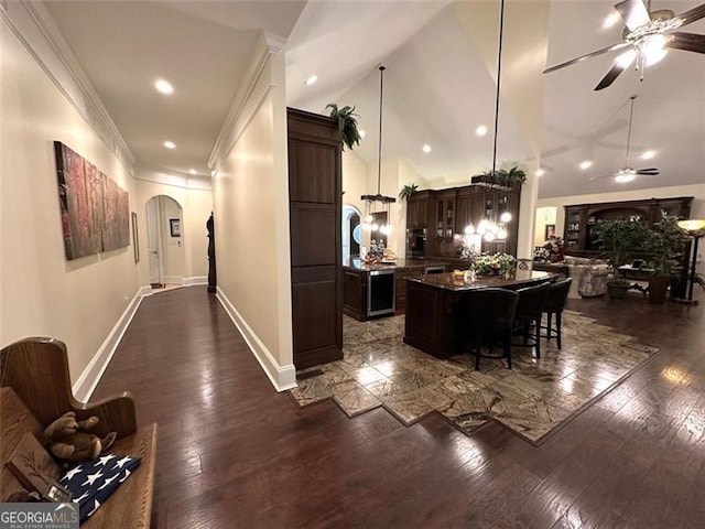 kitchen with a breakfast bar, dark wood-type flooring, ceiling fan, dark brown cabinets, and a kitchen island