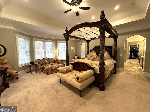 carpeted bedroom featuring a tray ceiling, ceiling fan, and ornamental molding