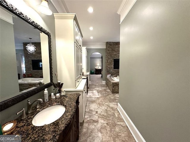 bathroom with a stone fireplace, crown molding, a bathtub, and vanity