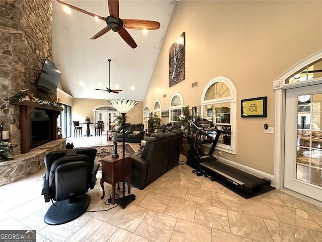 living room with french doors, high vaulted ceiling, ceiling fan, and a stone fireplace