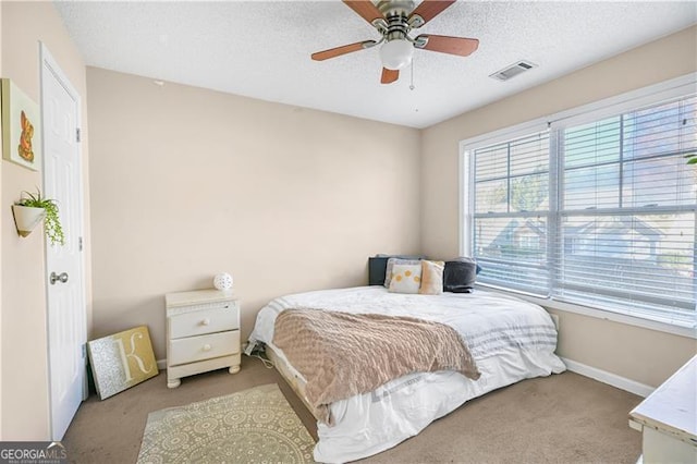 bedroom featuring ceiling fan, light colored carpet, and a textured ceiling