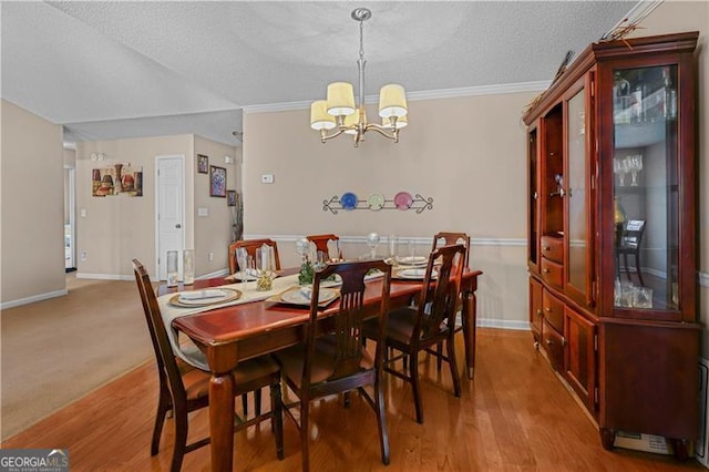 dining room featuring crown molding, light hardwood / wood-style floors, a textured ceiling, and an inviting chandelier