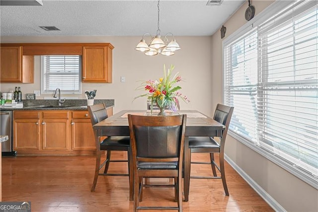 dining room featuring a notable chandelier, a healthy amount of sunlight, dark hardwood / wood-style floors, and sink