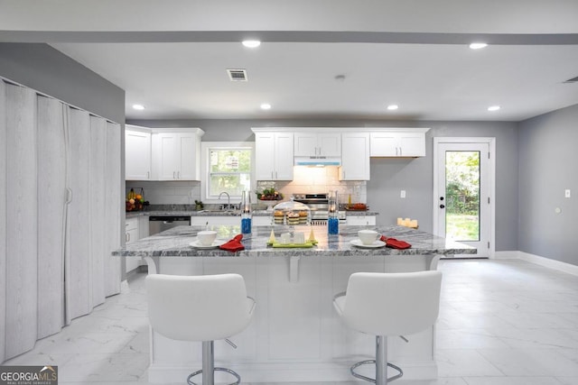 kitchen with white cabinets, decorative backsplash, a center island, and appliances with stainless steel finishes