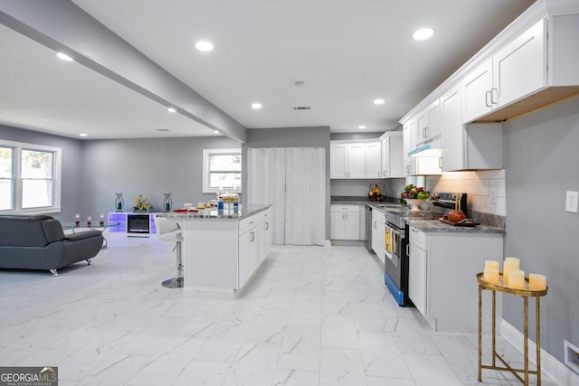 kitchen featuring light stone counters, a breakfast bar, white cabinets, and appliances with stainless steel finishes