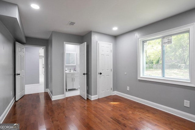 unfurnished bedroom featuring sink, dark wood-type flooring, and connected bathroom