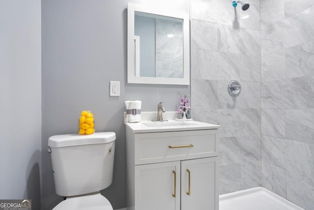 bathroom featuring a tile shower, vanity, and toilet