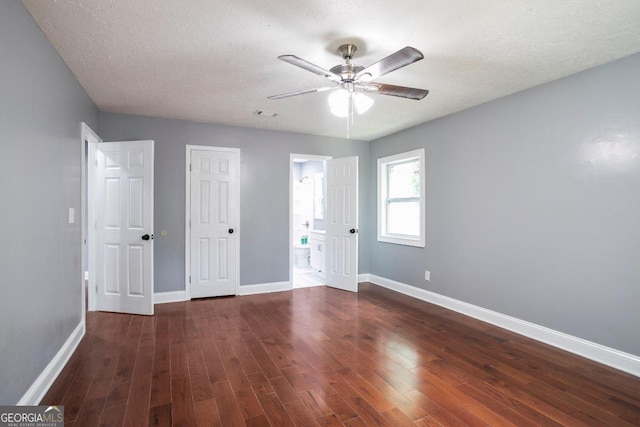 unfurnished bedroom with ceiling fan, dark hardwood / wood-style flooring, ensuite bathroom, and a textured ceiling