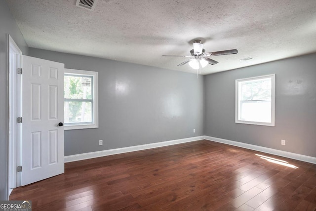 unfurnished room featuring a textured ceiling, dark wood-type flooring, and a healthy amount of sunlight