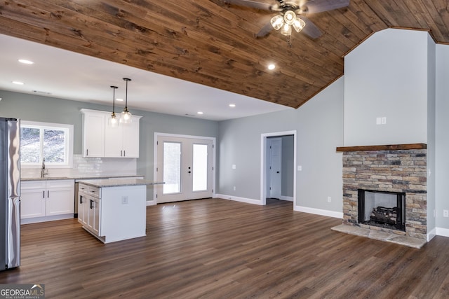 kitchen featuring light stone countertops, a kitchen island, white cabinets, and decorative light fixtures