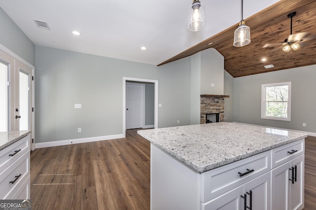 kitchen with a center island, hanging light fixtures, dark hardwood / wood-style flooring, a fireplace, and white cabinets