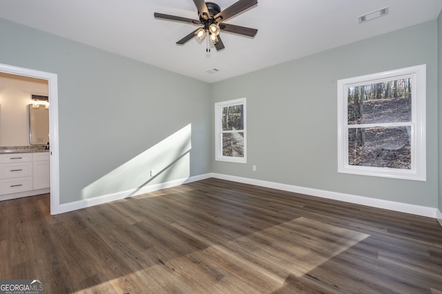 empty room with plenty of natural light, dark wood-type flooring, and ceiling fan