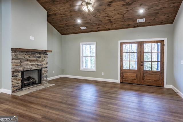 interior space with wood ceiling, plenty of natural light, dark hardwood / wood-style floors, and a stone fireplace