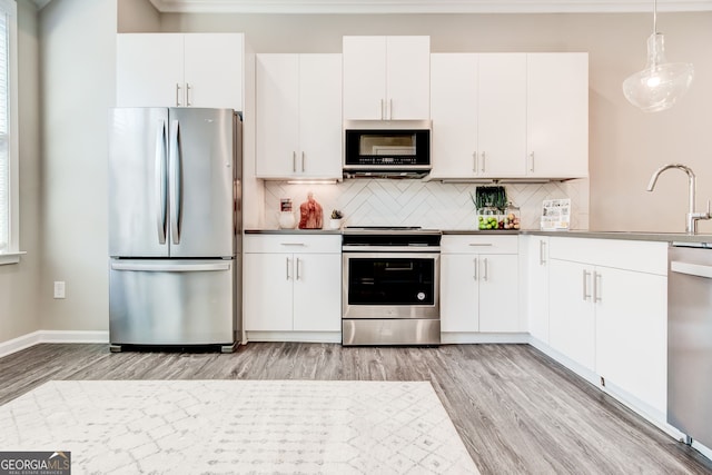 kitchen featuring pendant lighting, stainless steel appliances, white cabinetry, and light hardwood / wood-style flooring