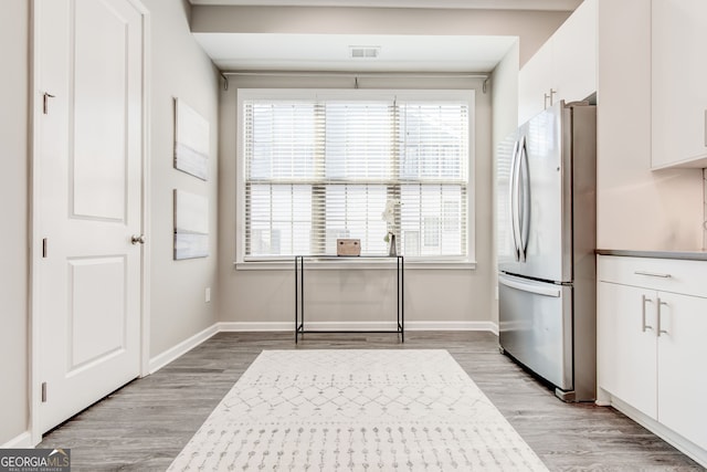 kitchen featuring white cabinetry, stainless steel fridge, and light wood-type flooring