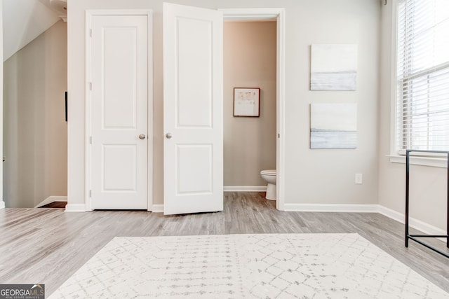 unfurnished bedroom with light wood-type flooring and ensuite bath