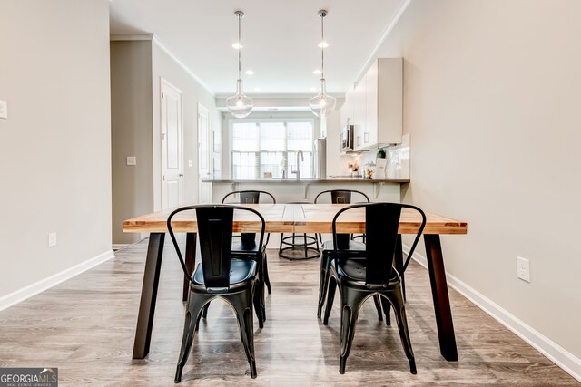 dining space featuring light wood-type flooring and crown molding