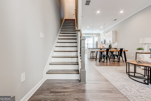 stairway with hardwood / wood-style floors and crown molding