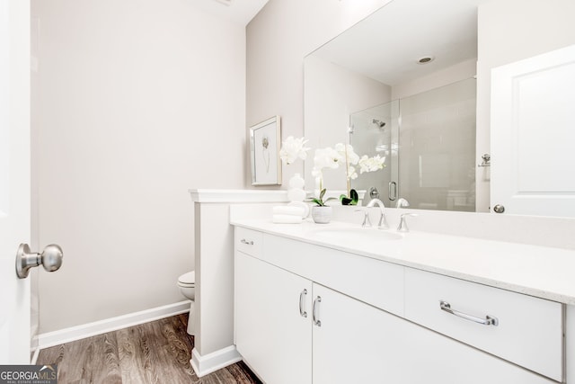 bathroom with hardwood / wood-style flooring, vanity, toilet, and an enclosed shower