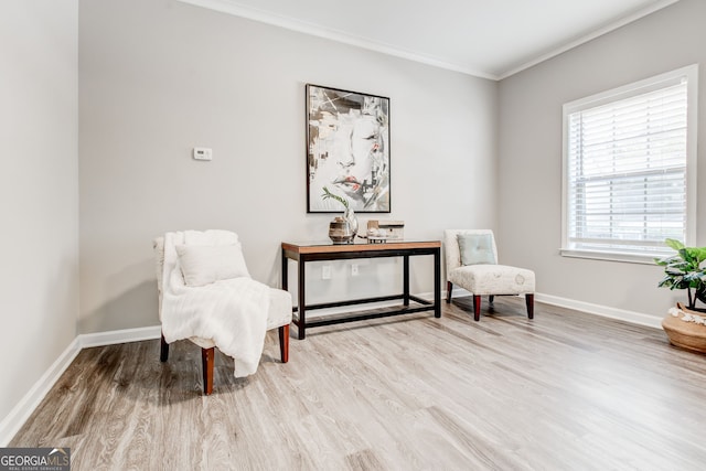 living area featuring crown molding and light hardwood / wood-style floors