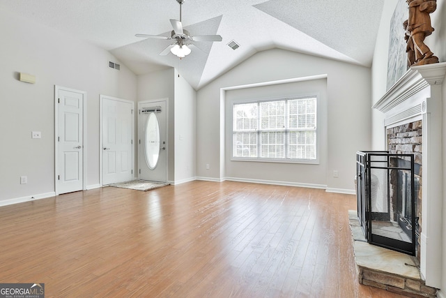 unfurnished living room with a textured ceiling, light hardwood / wood-style flooring, ceiling fan, and lofted ceiling