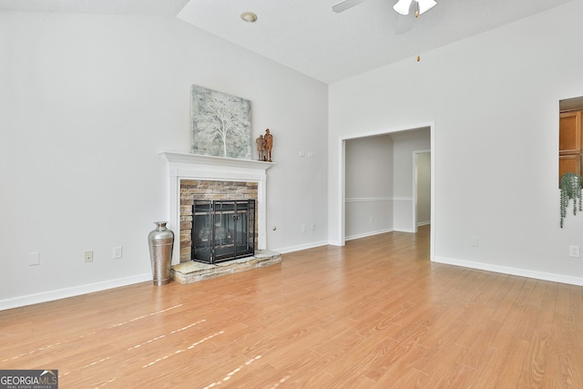 unfurnished living room featuring lofted ceiling, a stone fireplace, ceiling fan, a textured ceiling, and wood-type flooring