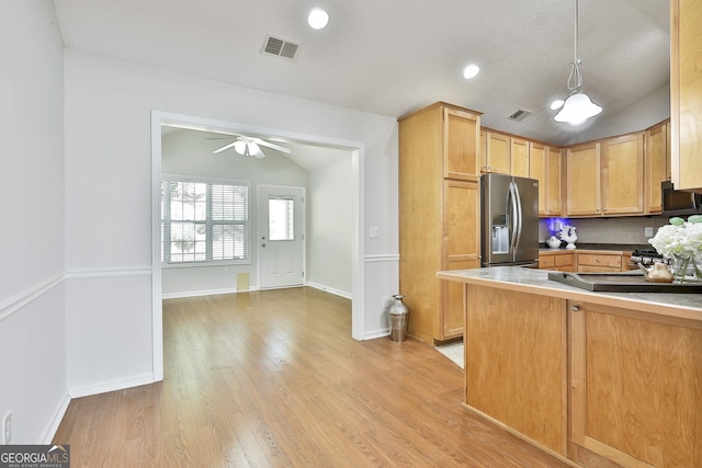 kitchen with stainless steel fridge, vaulted ceiling, ceiling fan, pendant lighting, and light hardwood / wood-style floors