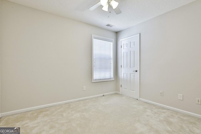 spare room featuring a textured ceiling, light colored carpet, and ceiling fan