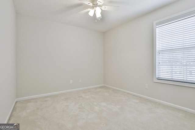 carpeted empty room featuring ceiling fan, plenty of natural light, and a textured ceiling