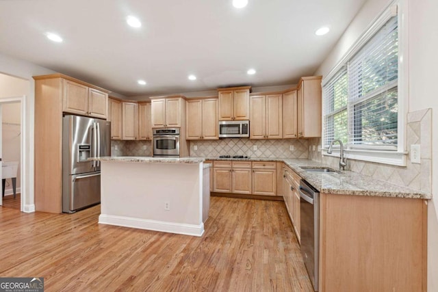 kitchen featuring light stone countertops, appliances with stainless steel finishes, light brown cabinetry, sink, and light hardwood / wood-style floors