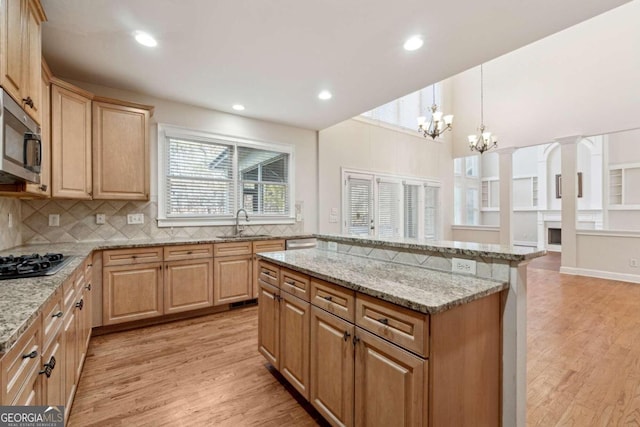 kitchen featuring sink, stainless steel appliances, light hardwood / wood-style flooring, pendant lighting, and a chandelier