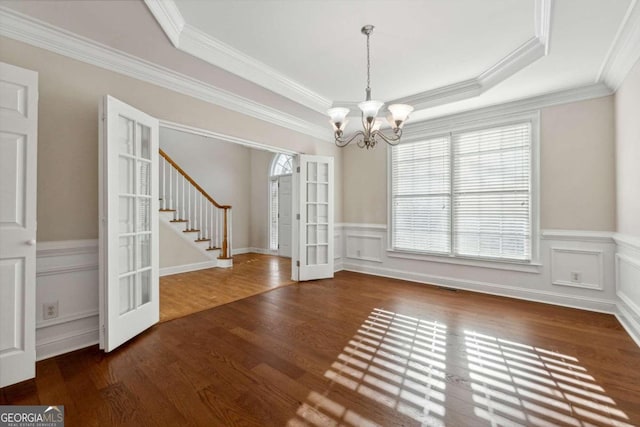 unfurnished dining area with dark hardwood / wood-style flooring, french doors, an inviting chandelier, and ornamental molding