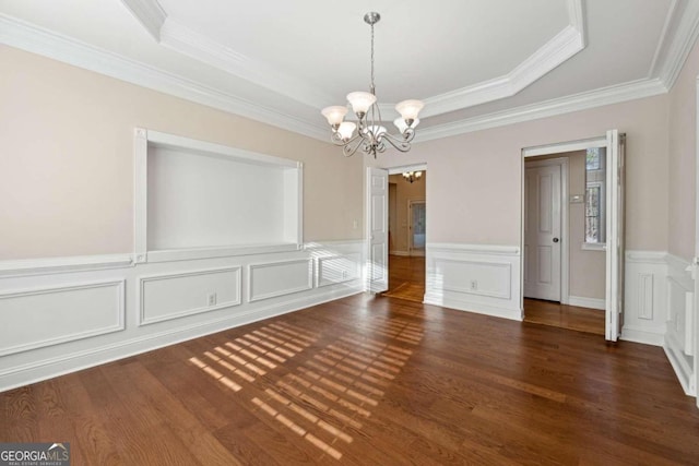 unfurnished dining area featuring dark hardwood / wood-style floors, a raised ceiling, crown molding, and an inviting chandelier