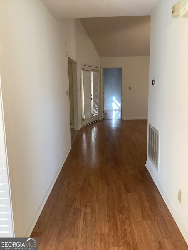 corridor featuring vaulted ceiling and wood-type flooring