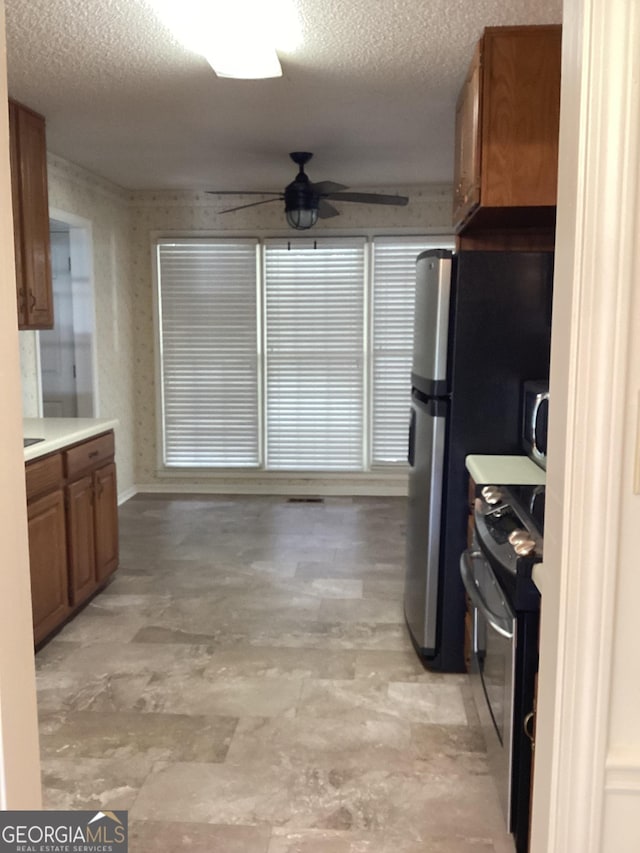 kitchen with appliances with stainless steel finishes, ceiling fan, and a textured ceiling