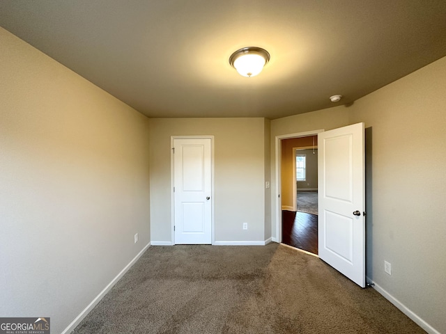 unfurnished bedroom with dark colored carpet