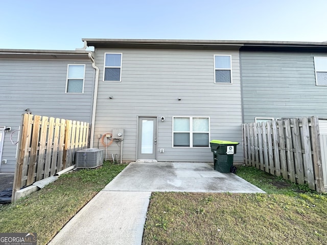 back of property featuring central AC unit, a patio area, and a yard