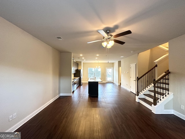 unfurnished living room with ceiling fan with notable chandelier, dark wood-type flooring, and sink