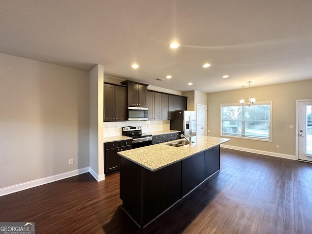 kitchen featuring sink, dark wood-type flooring, an inviting chandelier, an island with sink, and appliances with stainless steel finishes