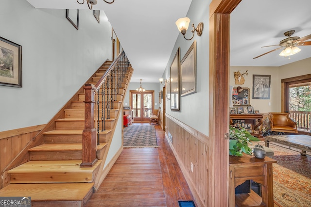 staircase with wood walls, ceiling fan, and hardwood / wood-style flooring