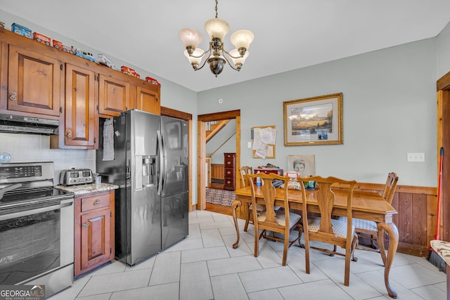 kitchen with black refrigerator with ice dispenser, stainless steel range with electric stovetop, exhaust hood, pendant lighting, and an inviting chandelier