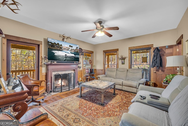 living room featuring ceiling fan, a fireplace, and wood-type flooring