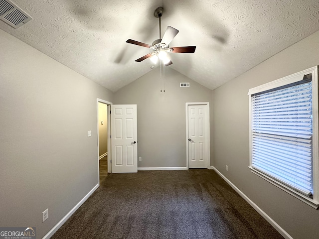 unfurnished bedroom featuring dark colored carpet, a textured ceiling, ceiling fan, and lofted ceiling