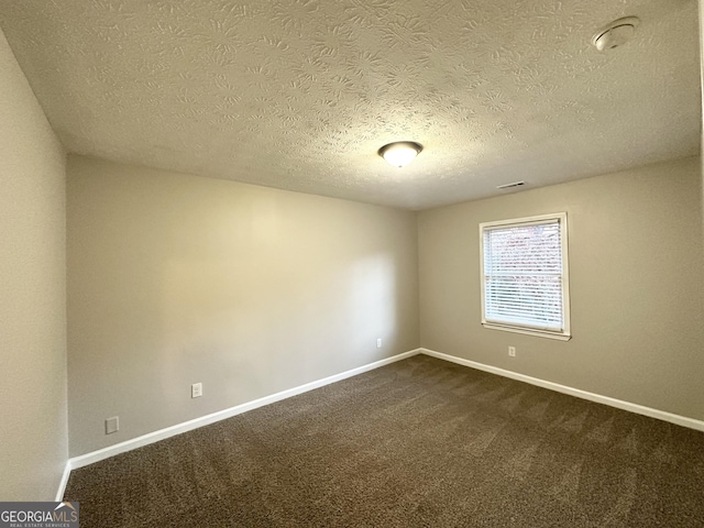 unfurnished room with a textured ceiling and dark colored carpet