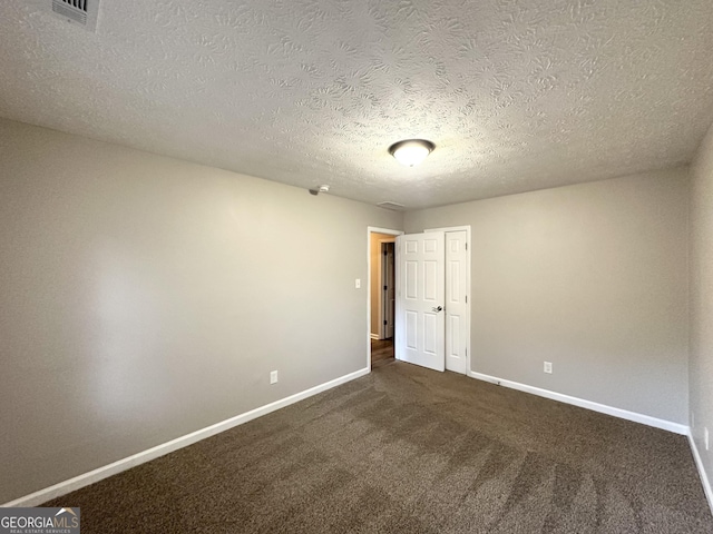 unfurnished room featuring dark colored carpet and a textured ceiling