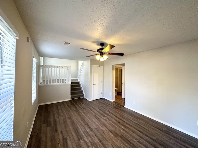 unfurnished room featuring ceiling fan, dark wood-type flooring, and a textured ceiling